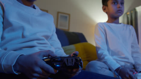Close-Up-On-Hands-Of-Two-Young-Boys-At-Home-Playing-With-Computer-Games-Console-On-TV-Holding-Controllers-Late-At-Night-5